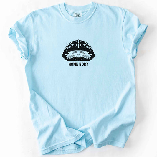 Chambray "Home Body" t-shirt on Comfort Colors tee, featuring a bold black graphic of a turtle peeking out from its shell above simple lettering. Funny turtle lover gift shirt for introverts and reptile enthusiasts.