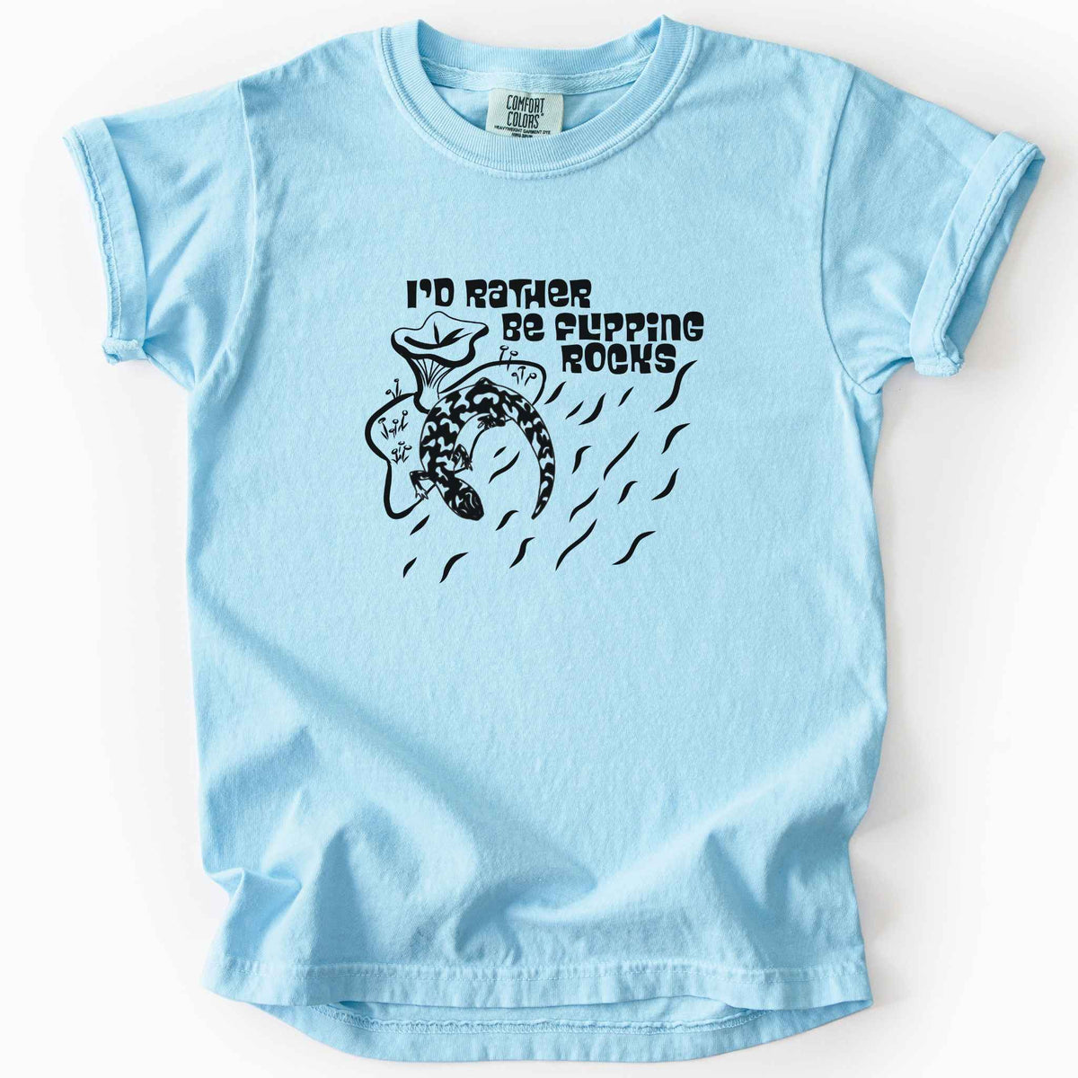 Chambray "I'd Rather Be Flipping Rocks" kids t-shirt on Comfort Colors tee, featuring a bold graphic of a curled salamander with mushrooms in a groovy retro font. Funny herpetology gift shirt for salamander hunters and amphibian enthusiasts.