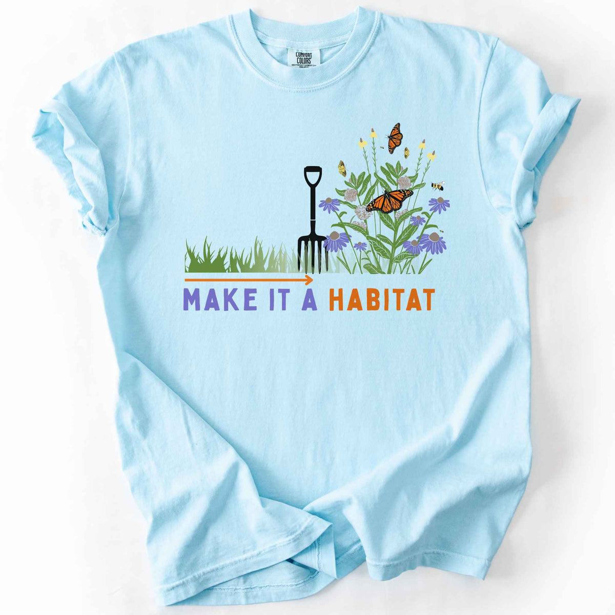 Chambray "Make It a Habitat" t-shirt on Comfort Colors tee, featuring a garden fork beside coneflowers and milkweed with monarch butterflies and bees, transforming grass into wildflowers. Gardener and native plant gift shirt for pollinator conservation fans.
