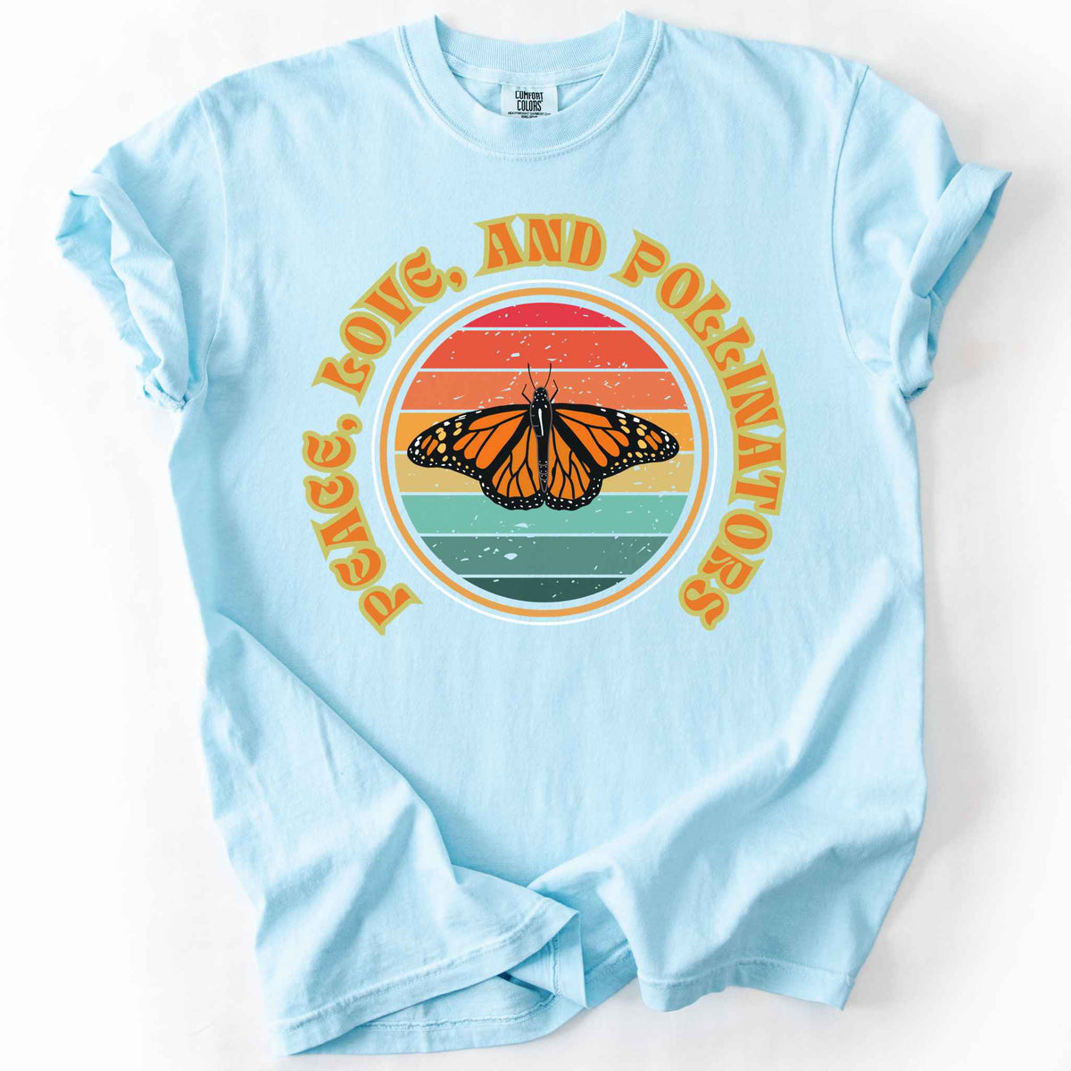 Chambray "Peace, Love, and Pollinators" t-shirt on Comfort Colors tee, featuring a monarch butterfly against a retro rainbow sunset circle design. Butterfly gardener and native plant gift shirt for pollinator conservation fans.