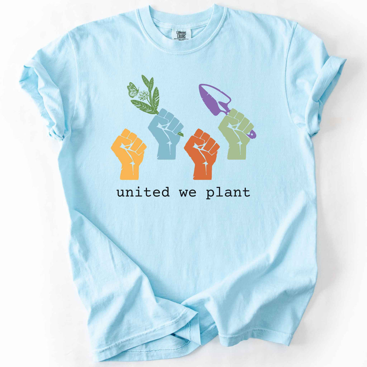 Chambray "United We Plant" t-shirt on Comfort Colors tee, featuring four colorful raised fists, one holding a plant sprig and another a garden trowel, above bold black text. Gardener and native plant gift shirt for community garden and conservation enthusiasts.