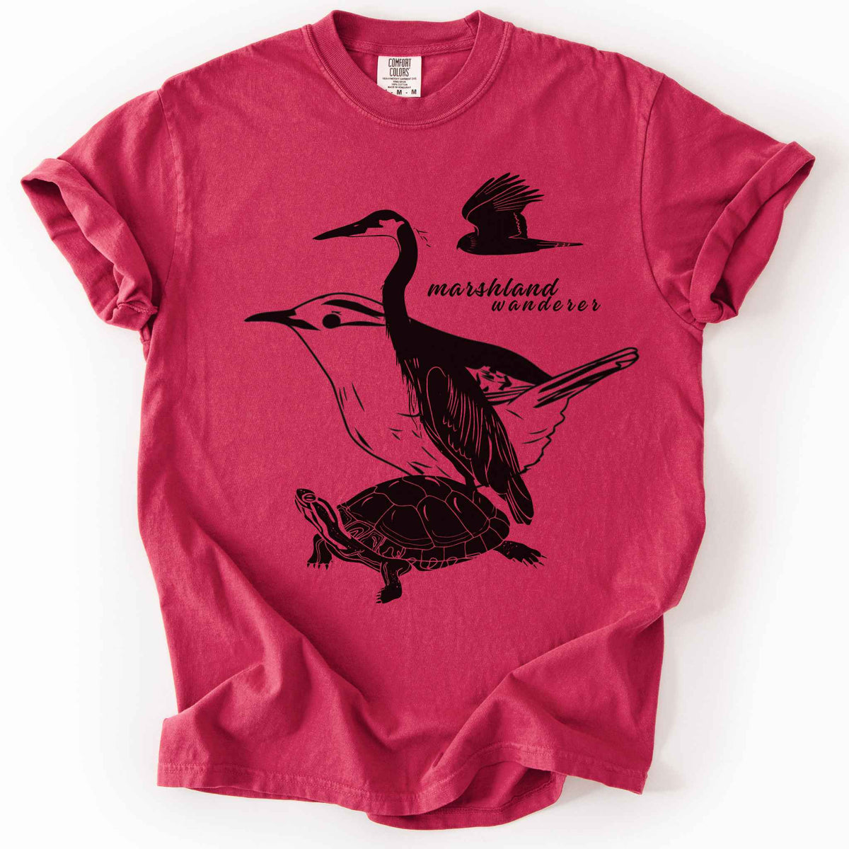 Chili "Marshland Wanderer" t-shirt on Comfort Colors tee, featuring a surreal black line art design blending a heron, marsh wren, turtle, and marsh harrier into one flowing wetland scene. Nature lover and wetland conservation gift shirt for birdwatching and wildlife enthusiasts.