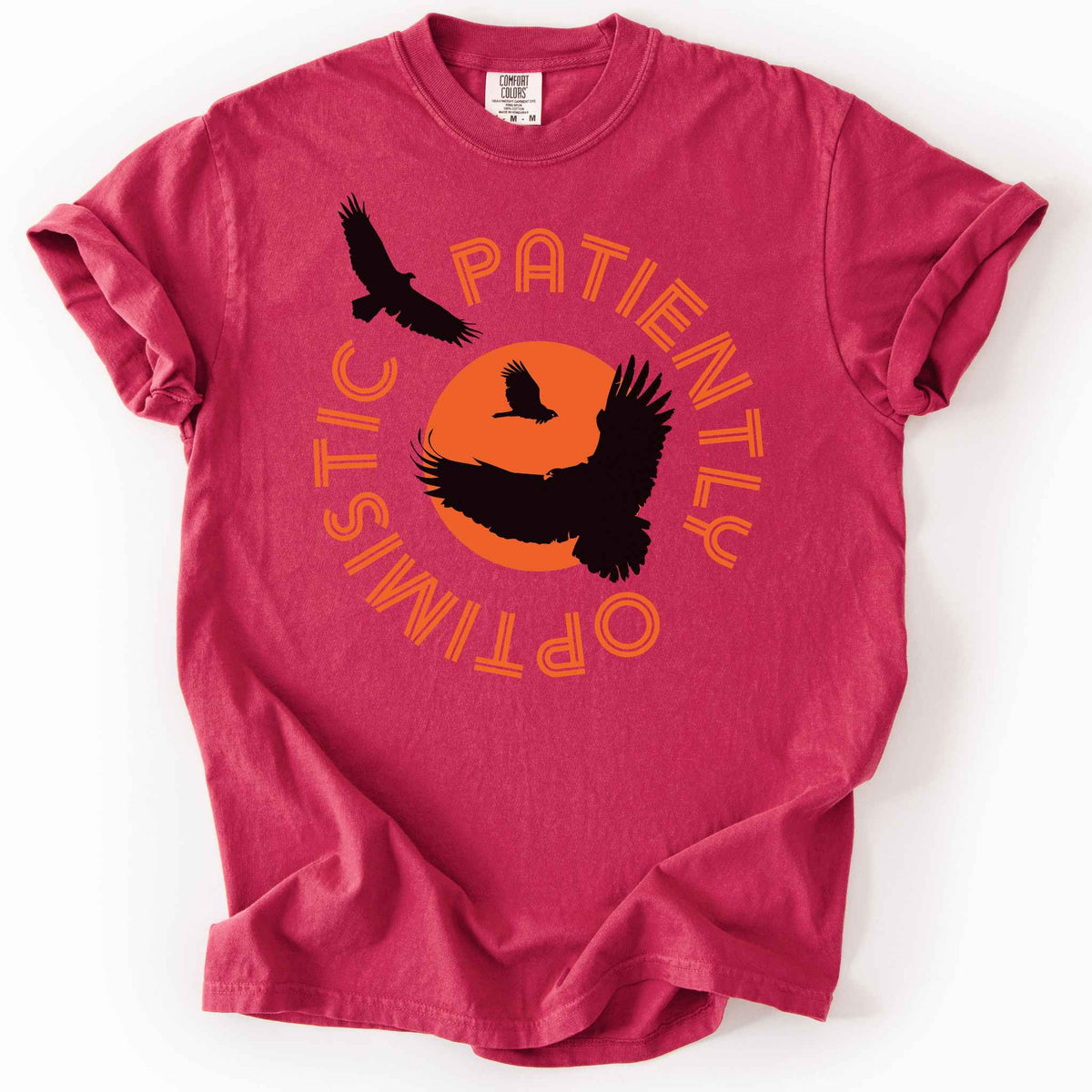 Chili "Patiently optimistic turkey vulture" t-shirt on comfort colors tee. Silhouette turkey vulture graphics against an orange sun surrounded by curved text. Bird lover and wildlife enthusiast gift. 
