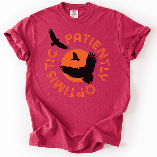 Chili "Patiently optimistic turkey vulture" t-shirt on comfort colors tee. Silhouette turkey vulture graphics against an orange sun surrounded by curved text. Bird lover and wildlife enthusiast gift. 