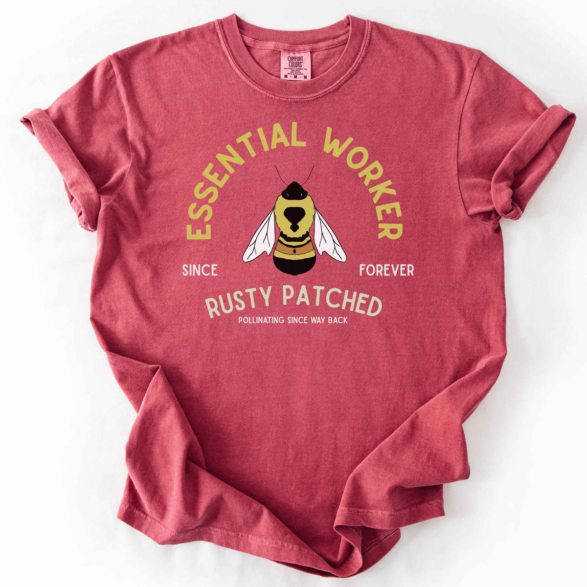 Crimson "Essential Worker, Rusty Patched, Pollinating Since Way Back" t-shirt on Comfort Colors tee, featuring an illustrated bumblebee in a circular design. Funny bee lover gift shirt for pollinator and rusty patched bumblebee conservation fans.