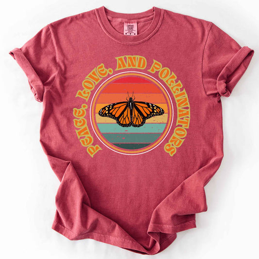 Crimson "Peace, Love, and Pollinators" t-shirt on Comfort Colors tee, featuring a monarch butterfly against a retro rainbow sunset circle design. Butterfly gardener and native plant gift shirt for pollinator conservation fans.