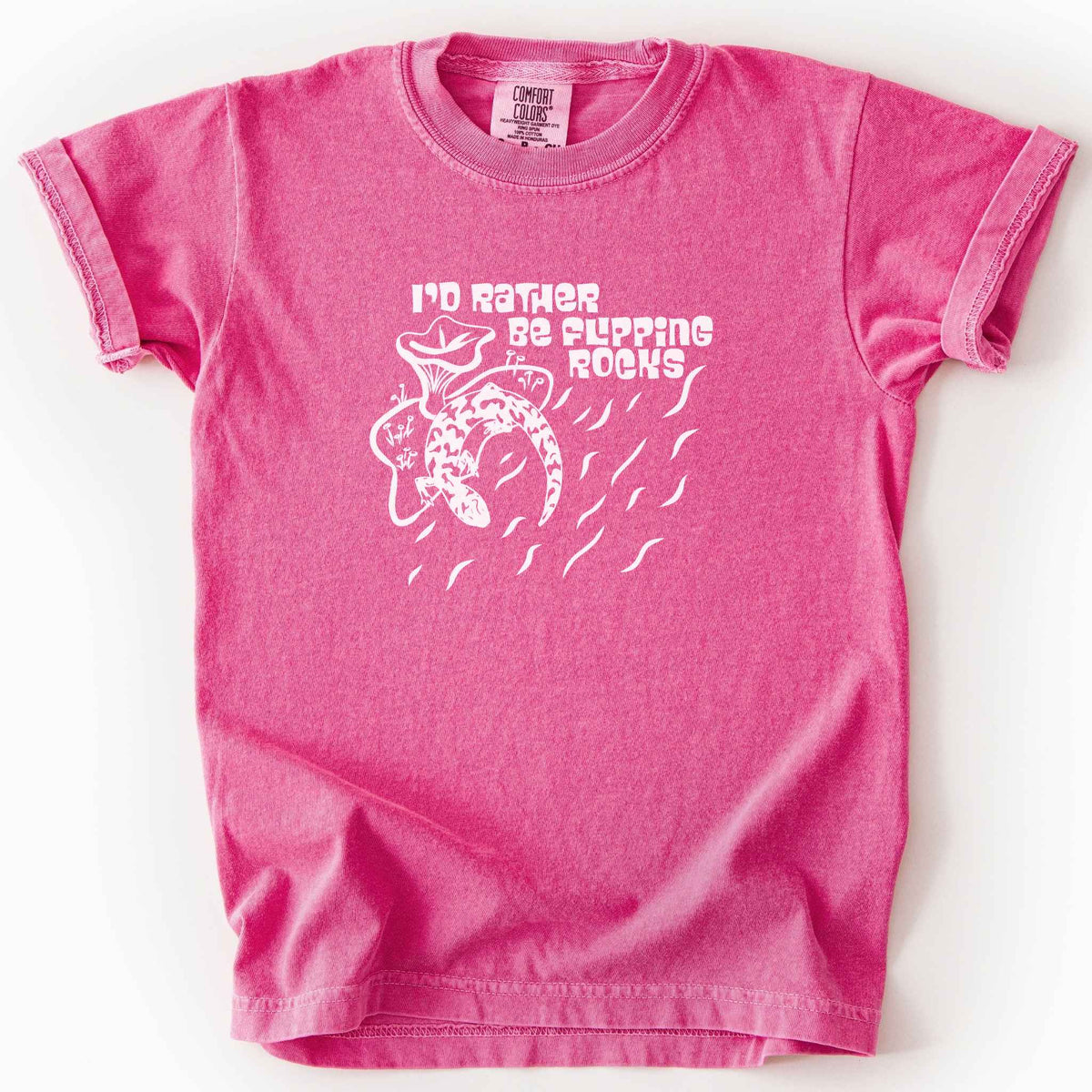 Crunchberry "I'd Rather Be Flipping Rocks" kids t-shirt on Comfort Colors tee, featuring a bold graphic of a curled salamander with mushrooms in a groovy retro font. Funny herpetology gift shirt for salamander hunters and amphibian enthusiasts.