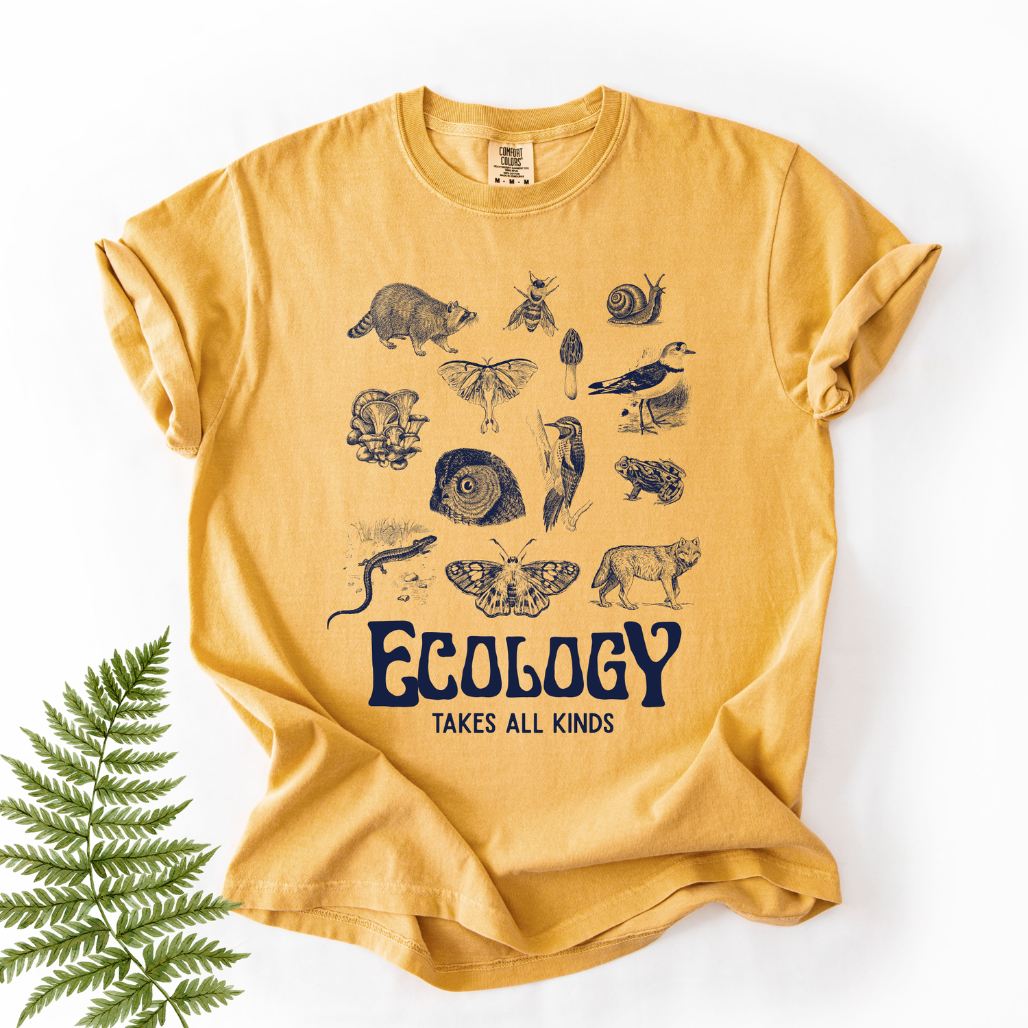 Yellow t-shirt with nature-themed graphics and 'Ecology Takes All Kinds' text on a white background.