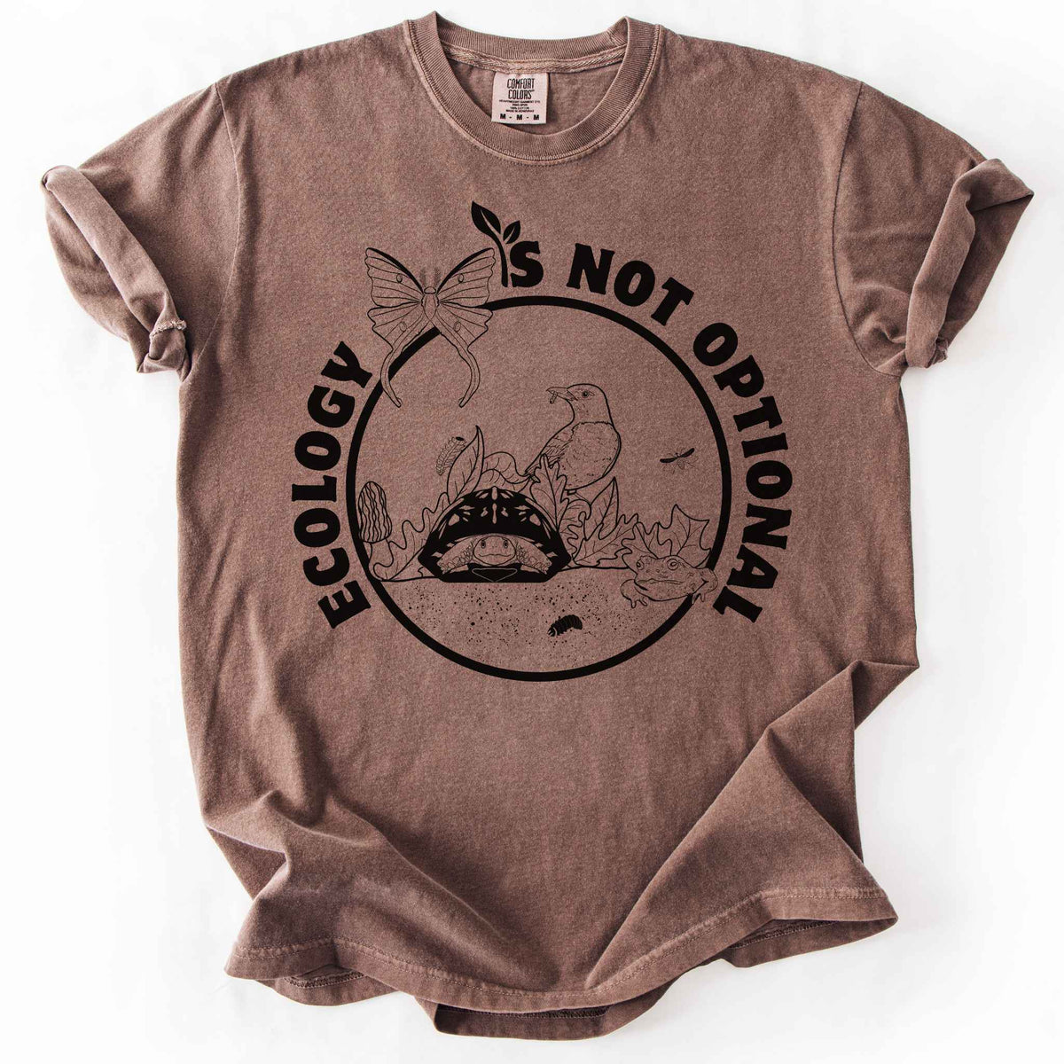 Espresso "Ecology Is Not Optional" t-shirt on Comfort Colors tee, featuring a black circle badge with a box turtle, bird, luna moth, frog, and mushrooms in an ecosystem scene. Nature lover and biology gift shirt for ecologists and conservation enthusiasts.