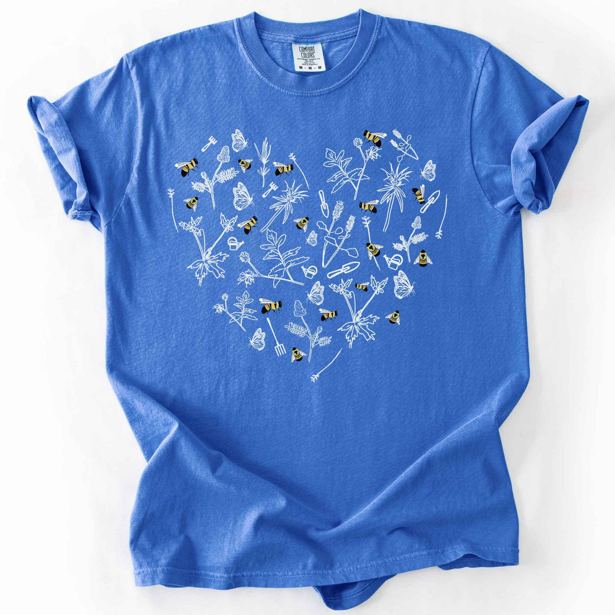 Flo Blue "Rusty Patch Bumblebee" t-shirt on Comfort Colors tee, featuring a heart shaped arrangement of hand-drawn white wildflowers, garden tools, butterflies, and colorful bees. Gardener and pollinator lover gift shirt for bee conservation and nature enthusiasts.