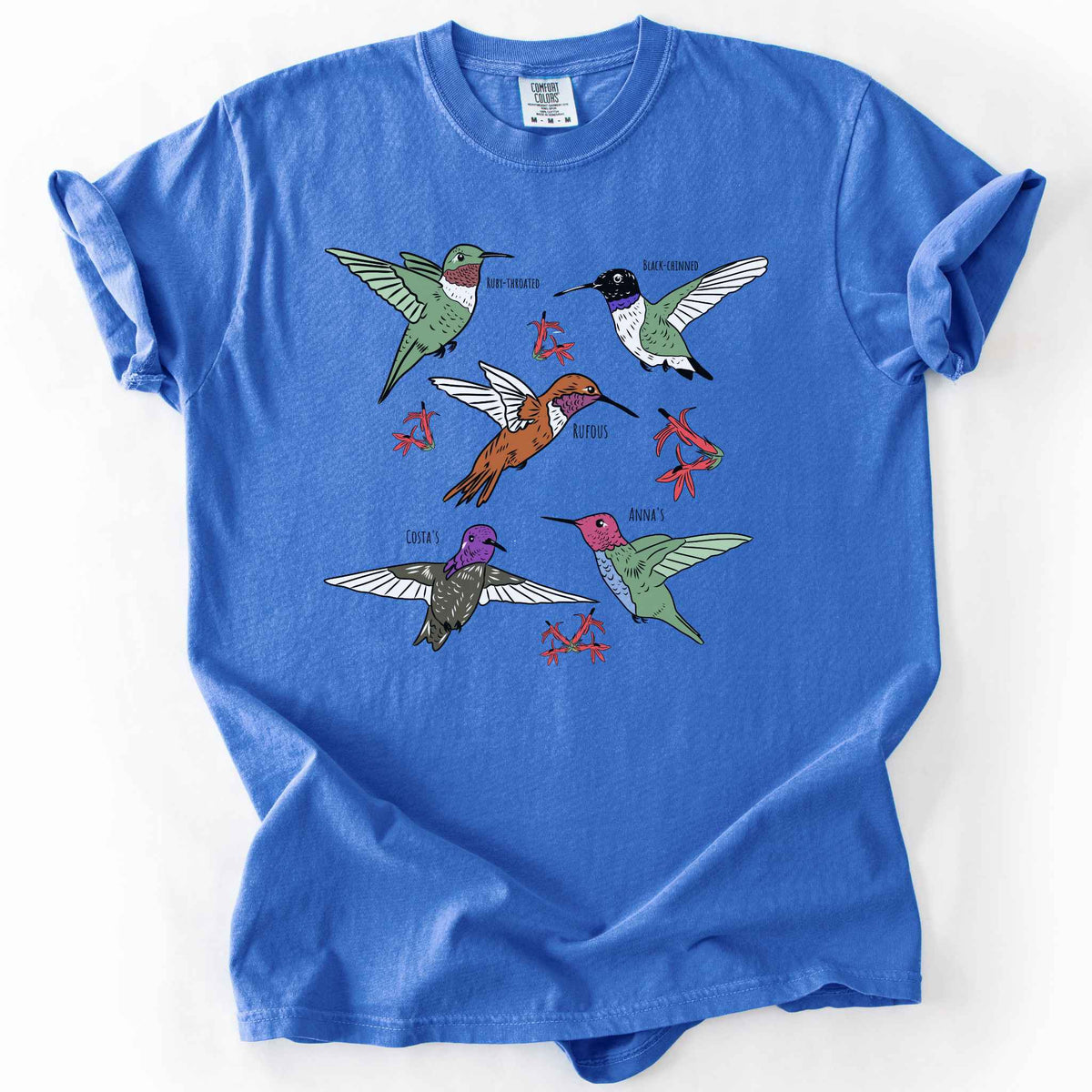 Flo Blue "hummingbirds" t-shirt on Comfort Colors tee, featuring five illustrated hummingbird species including Ruby Throated, Rufous, and Anna's, each labeled and shown among red flowers. Birdwatcher and hummingbird lover gift shirt for wildlife and nature enthusiasts.