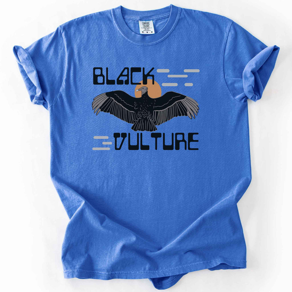 Flo blue "Black Vulture" t-shirt on Comfort Colors tee, featuring a vulture with spread wings against an orange sun with bold geometric lettering. Birdwatcher and scavenger lover gift shirt for wildlife and nature enthusiasts.
