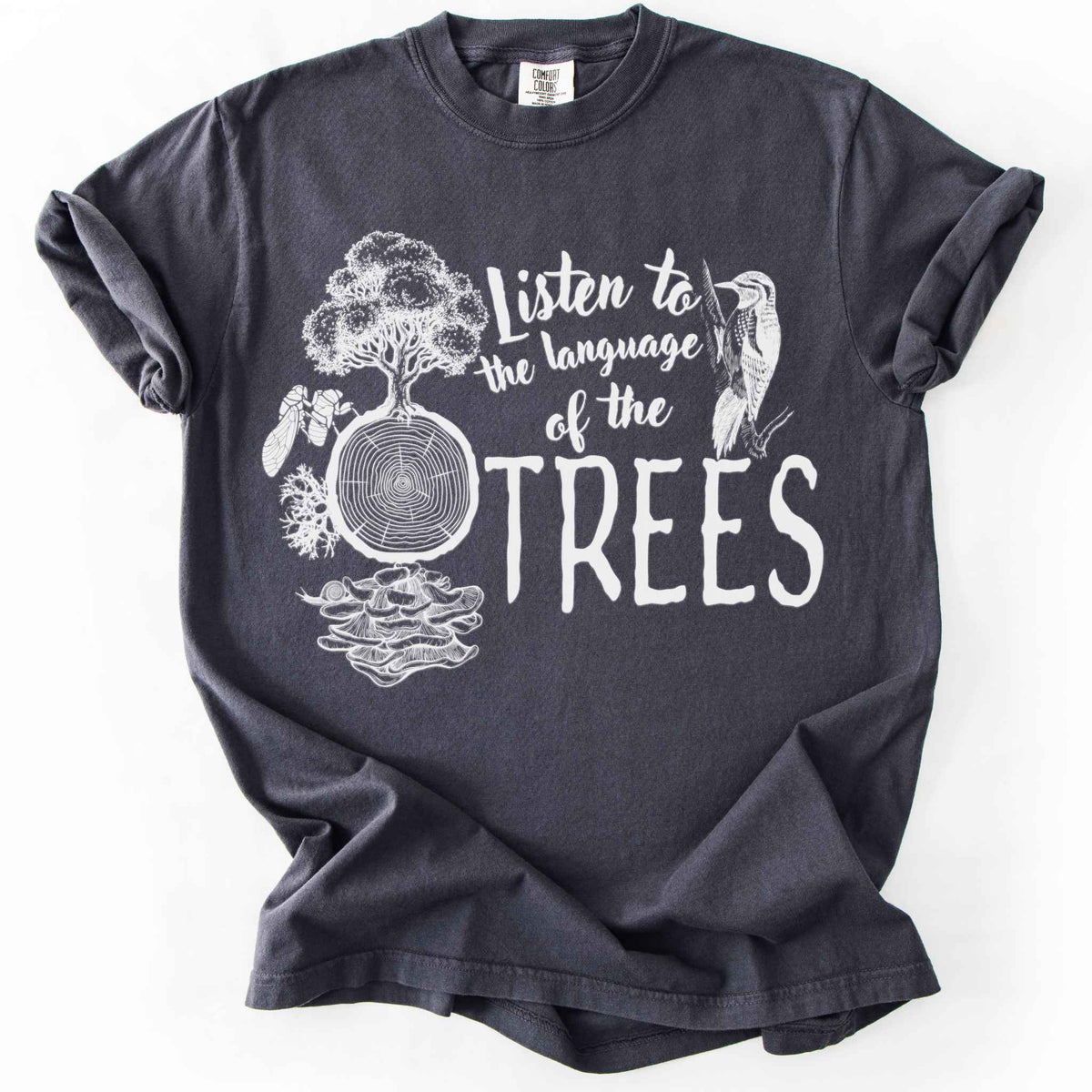 Graphite "Listen to the Language of the Trees" t-shirt on Comfort Colors tee, featuring a tree, tree rings, woodpecker, cicada, and mushrooms in white. Nature lover and forest ecology gift shirt for tree huggers and outdoor enthusiasts.