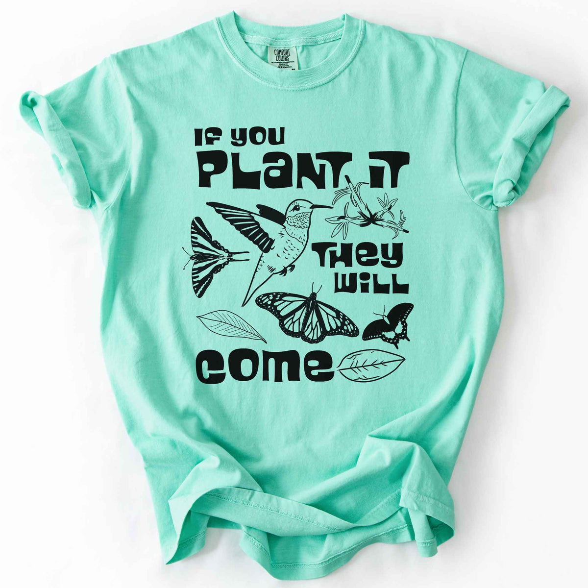 Island Reef "If You Plant It, They Will Come" t-shirt on Comfort Colors tee, featuring a hummingbird surrounded by butterflies and flowers with bold black lettering and line art style. Gardener and native plant gift shirt for pollinator conservation fans.