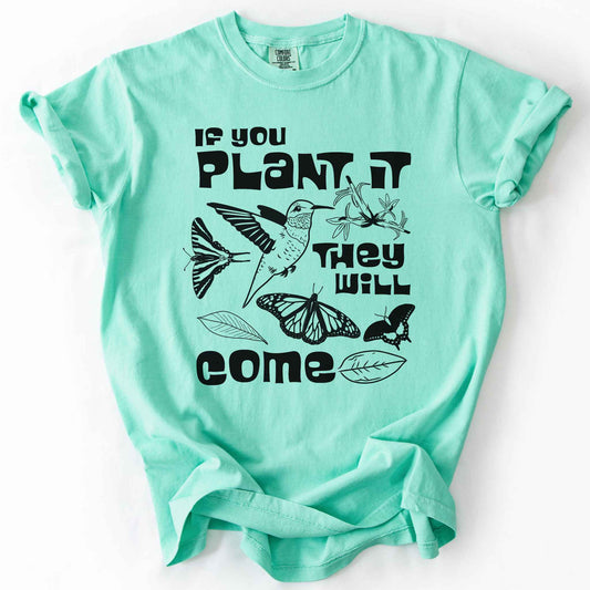Island Reef "If You Plant It, They Will Come" t-shirt on Comfort Colors tee, featuring a hummingbird surrounded by butterflies and flowers with bold black lettering and line art style. Gardener and native plant gift shirt for pollinator conservation fans.