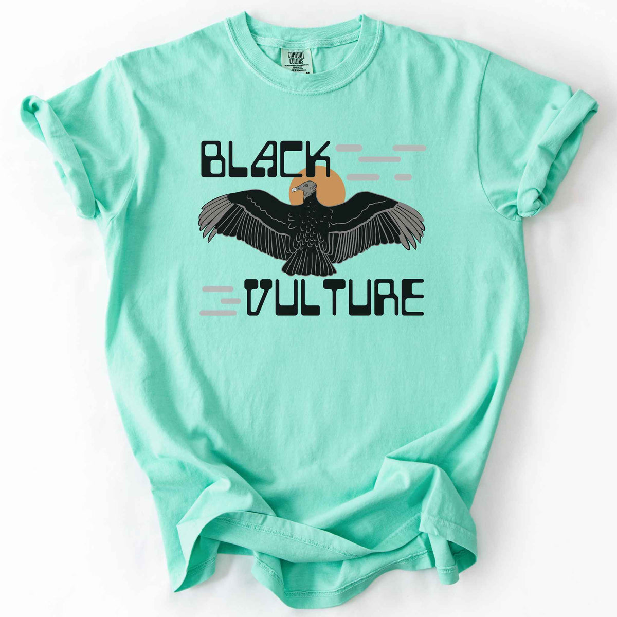 Island reef "Black Vulture" t-shirt on Comfort Colors tee, featuring a vulture with spread wings against an orange sun with bold geometric lettering. Birdwatcher and scavenger lover gift shirt for wildlife and nature enthusiasts.