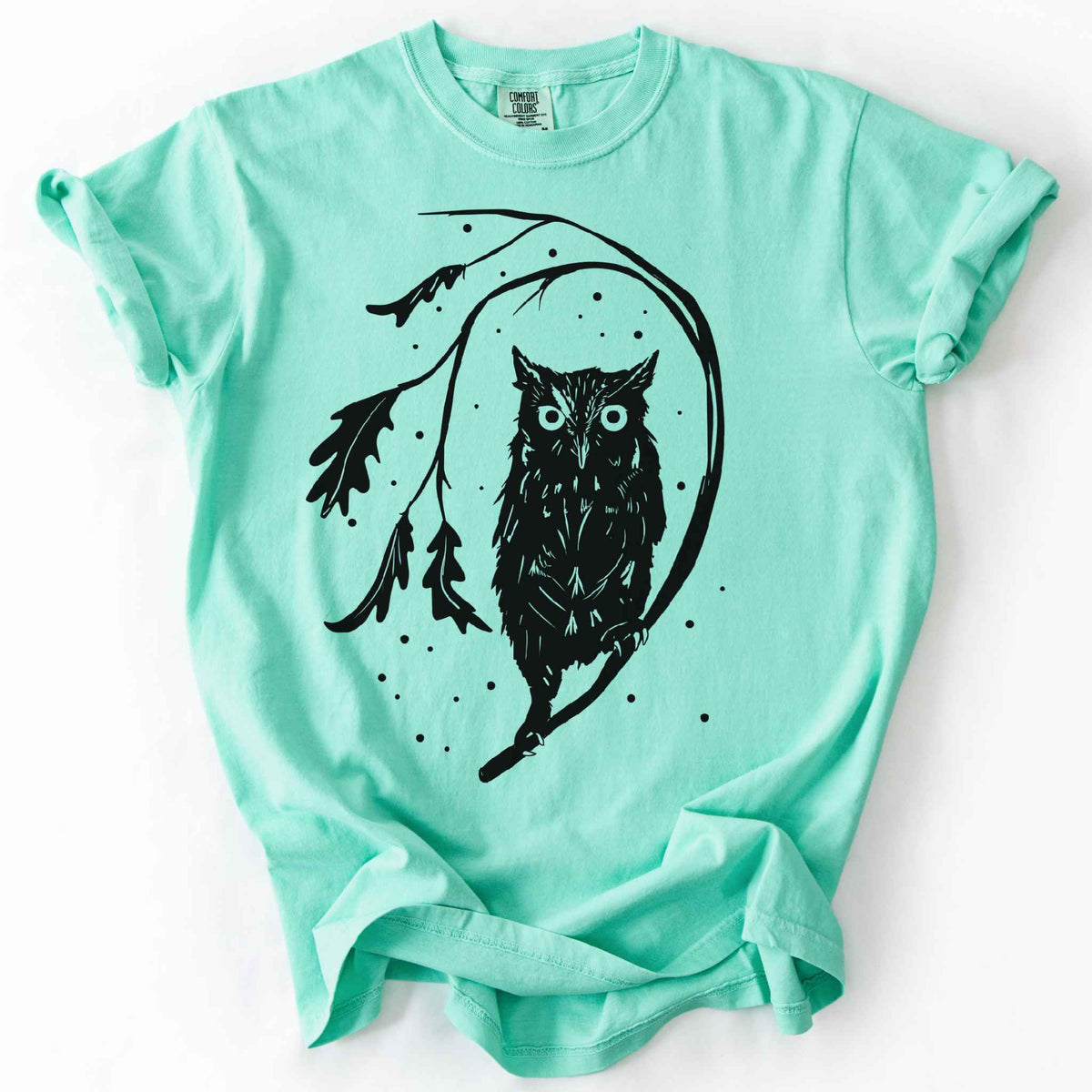 Island reef "Eastern Screech starry night" owl t-shirt on Comfort Colors tee, featuring a bold black illustration of a screech owl perched on a leafy branch with scattered dots for stars. Birdwatcher and owl lover gift shirt for wildlife and nature enthusiasts.