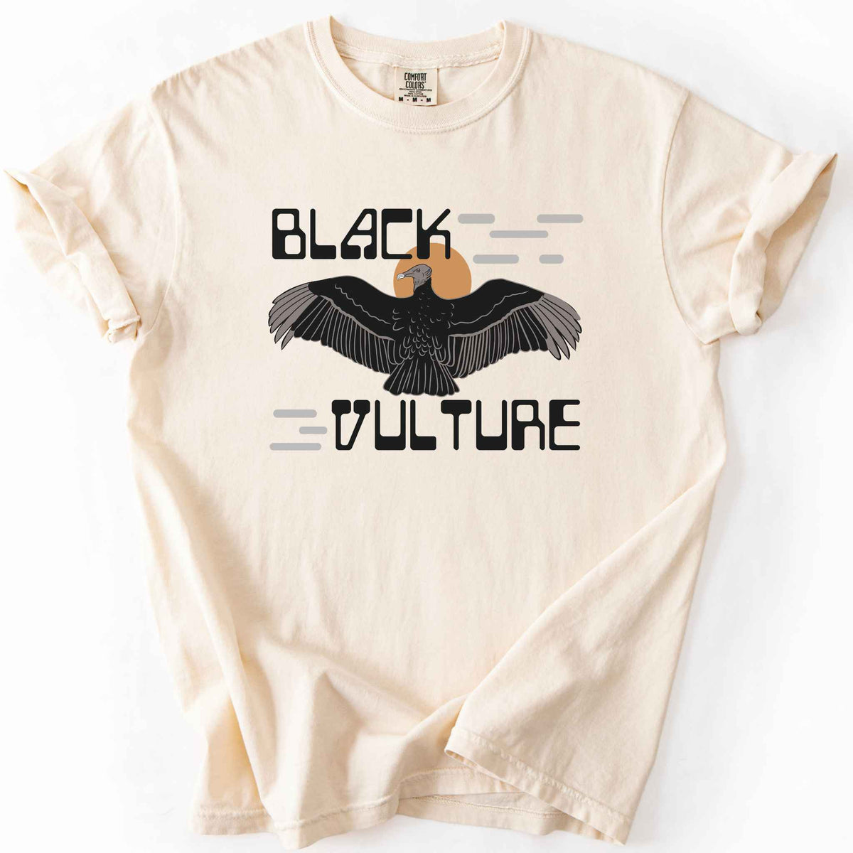 Ivory "Black Vulture" t-shirt on Comfort Colors tee, featuring a vulture with spread wings against an orange sun with bold geometric lettering. Birdwatcher and scavenger lover gift shirt for wildlife and nature enthusiasts.