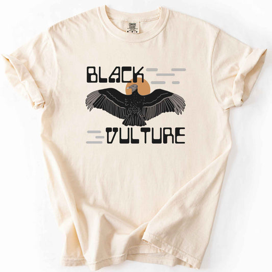 Ivory "Black Vulture" t-shirt on Comfort Colors tee, featuring a vulture with spread wings against an orange sun with bold geometric lettering. Birdwatcher and scavenger lover gift shirt for wildlife and nature enthusiasts.