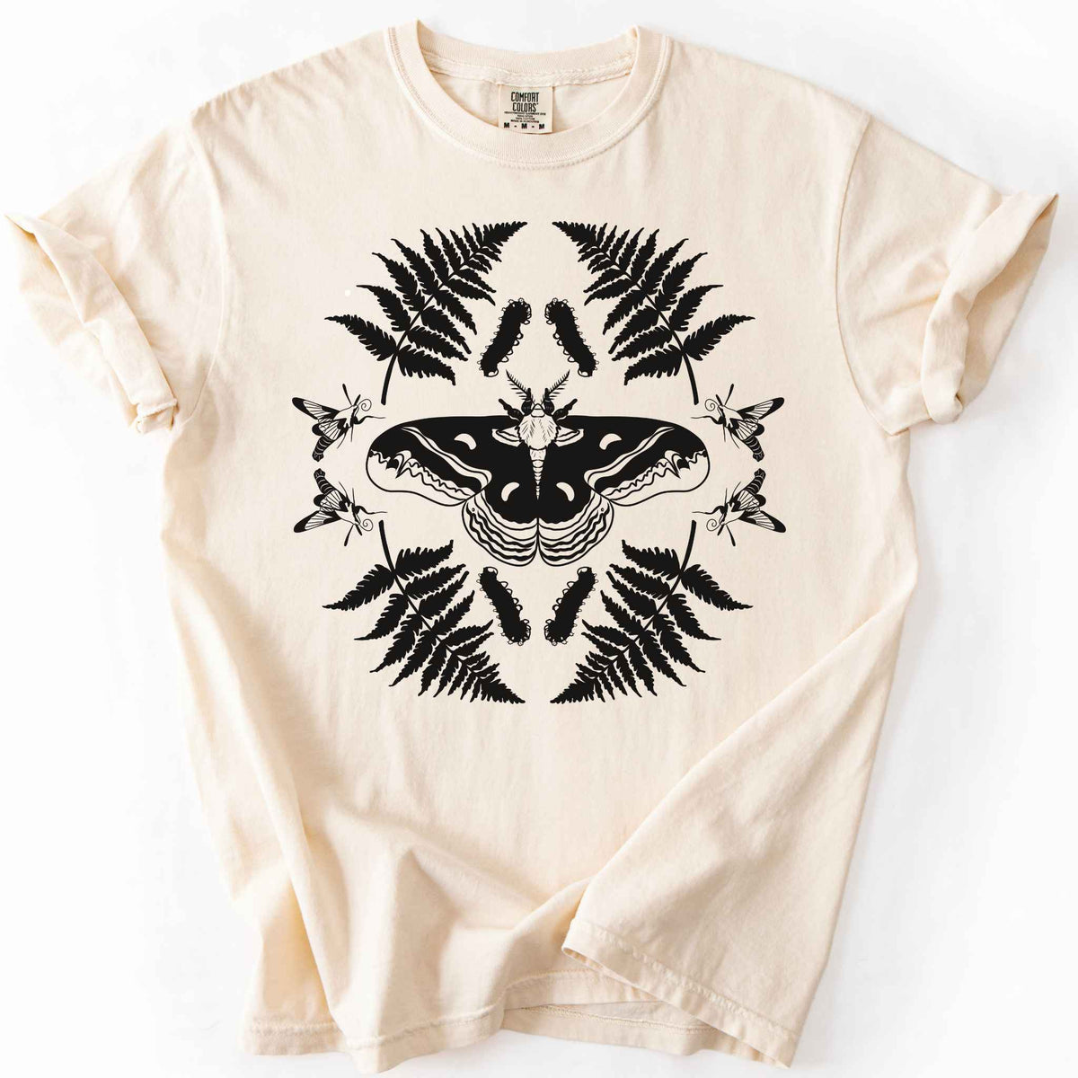 Ivory "Cecropia moth" t-shirt on Comfort Colors tee, featuring a bold black symmetrical design of a moth surrounded by ferns and hummingbird moths in a mirrored botanical pattern. Nature lover and moth enthusiast gift shirt for entomology and cottagecore fans.