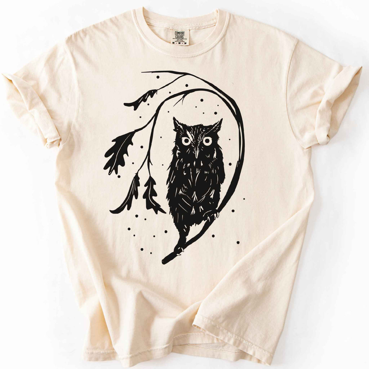 Ivory "Eastern Screech starry night" owl t-shirt on Comfort Colors tee, featuring a bold black illustration of a screech owl perched on a leafy branch with scattered dots for stars. Birdwatcher and owl lover gift shirt for wildlife and nature enthusiasts.