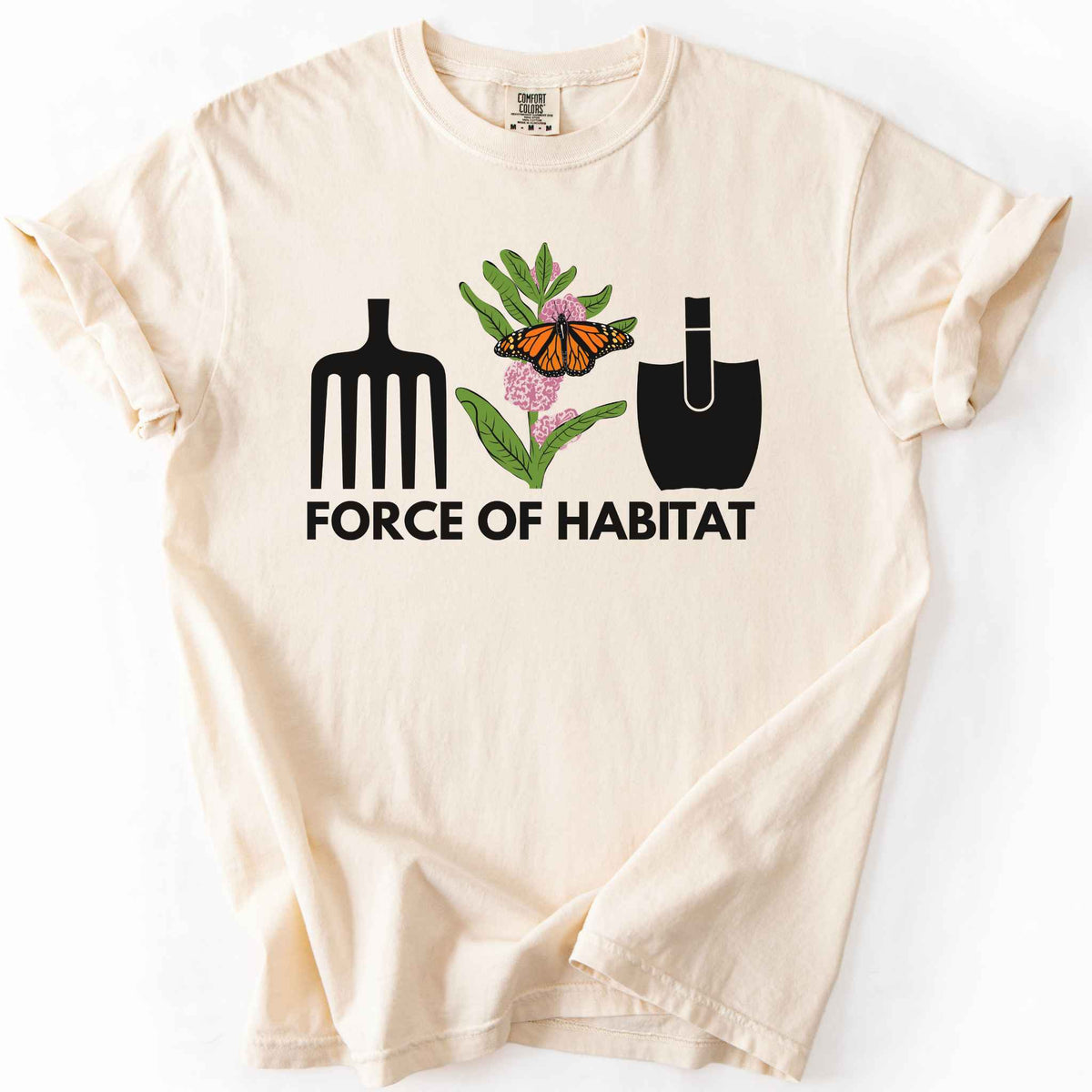 Ivory "Force of Habitat: monarch" t-shirt on Comfort Colors tee, featuring garden tool graphics flanking a hand-drawn monarch butterfly on milkweed flowers with bold black text below. Gardener and native plant gift shirt for pollinator conservation fans.