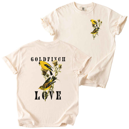 Ivory "Goldfinch Love" t-shirt on comfort colors tee. Featuring a small graphic of pair of goldfinch on a thistle plant placed on the front, and a large copy inbetween bold text on the back. Bird lover gift and wildlife inspired apparel.