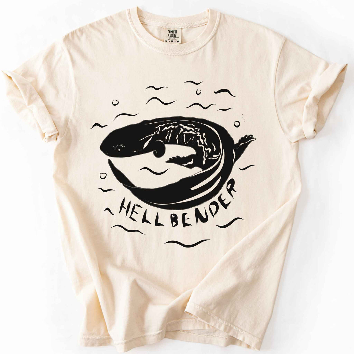 Ivory "Hellbender" t-shirt on Comfort Colors tee, featuring a bold graphic of a curled hellbender salamander surrounded by stylized water splashes and bubbles. Amphibian and herpetology lover gift shirt for salamander and wildlife enthusiasts.