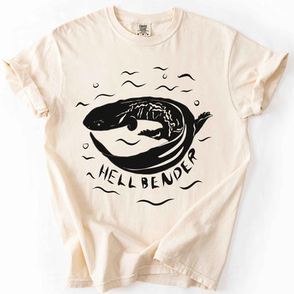 Ivory "Hellbender" t-shirt on Comfort Colors tee, featuring a bold graphic of a curled hellbender salamander surrounded by stylized water splashes and bubbles. Amphibian and herpetology lover gift shirt for salamander and wildlife enthusiasts.