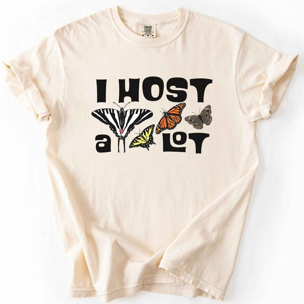 Ivory "I Host a Lot" t-shirt on Comfort Colors tee, featuring four butterfly species graphics including a Zebra Swallowtail and Monarch with bold black lettering text. Funny gardener and butterfly host plant gift shirt for pollinator enthusiasts.