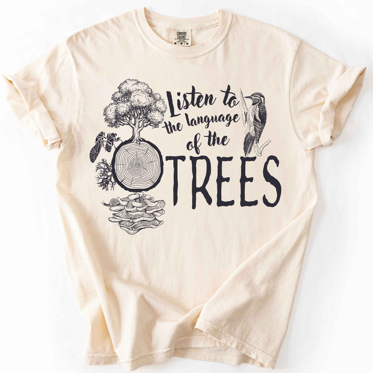 Ivory "Listen to the Language of the Trees" t-shirt on Comfort Colors tee, featuring a tree, tree rings, woodpecker, cicada, and mushrooms in white. Nature lover and forest ecology gift shirt for tree huggers and outdoor enthusiasts.