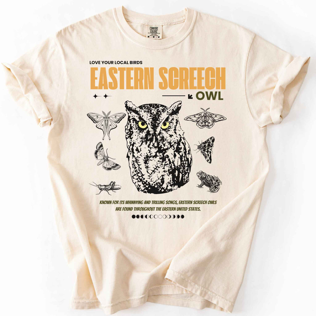 Ivory "Love Your Local Birds, Eastern Screech Owl" t-shirt on Comfort Colors tee, featuring a detailed owl portrait surrounded by moths, a frog, and a grasshopper with orange lettering and educational text. Birdwatcher and owl lover gift shirt for wildlife and nature enthusiasts.