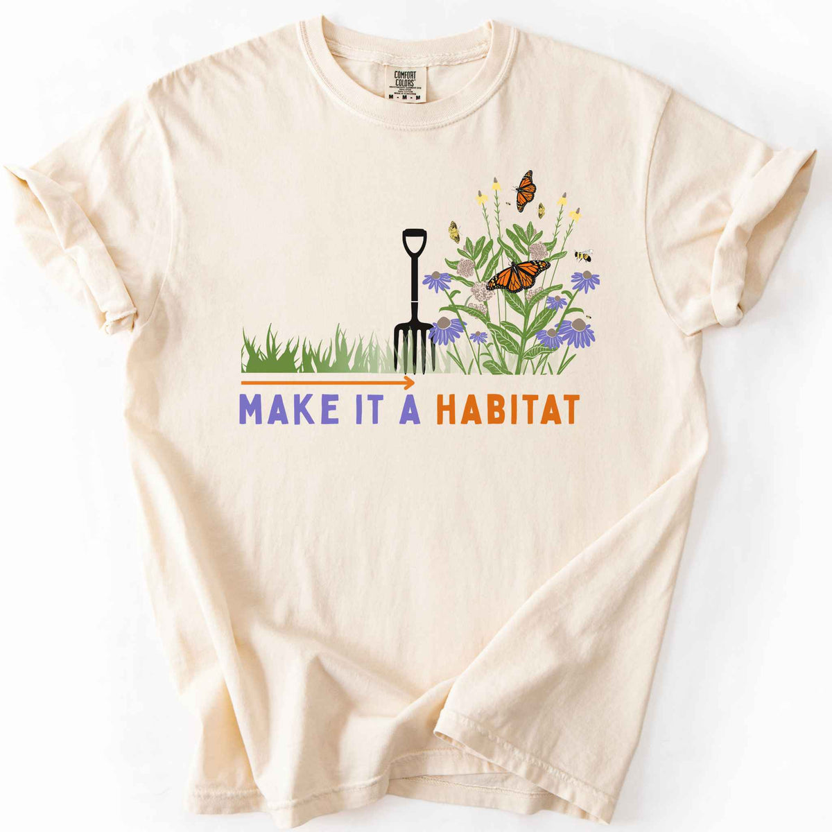 Ivory "Make It a Habitat" t-shirt on Comfort Colors tee, featuring a garden fork beside coneflowers and milkweed with monarch butterflies and bees, transforming grass into wildflowers. Gardener and native plant gift shirt for pollinator conservation fans.