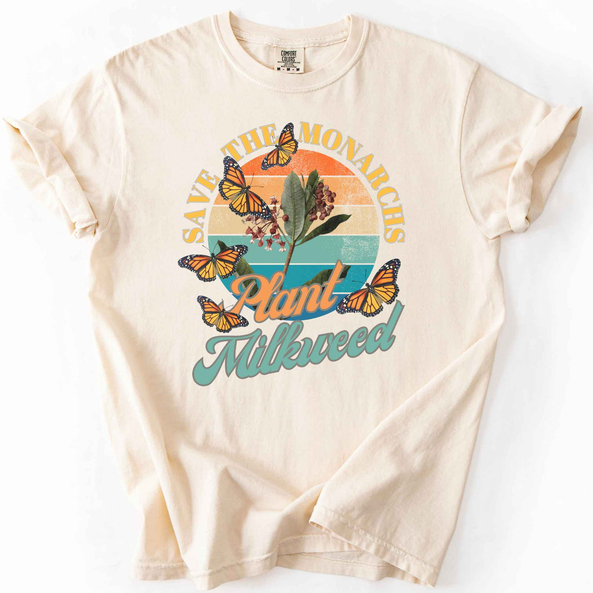 Ivory "Save the Monarchs, Plant Milkweed" t-shirt on Comfort Colors tee, featuring monarch butterflies fluttering around a milkweed plant against a retro sunset design. Butterfly gardener and native plant gift shirt for Monarch conservation fans.