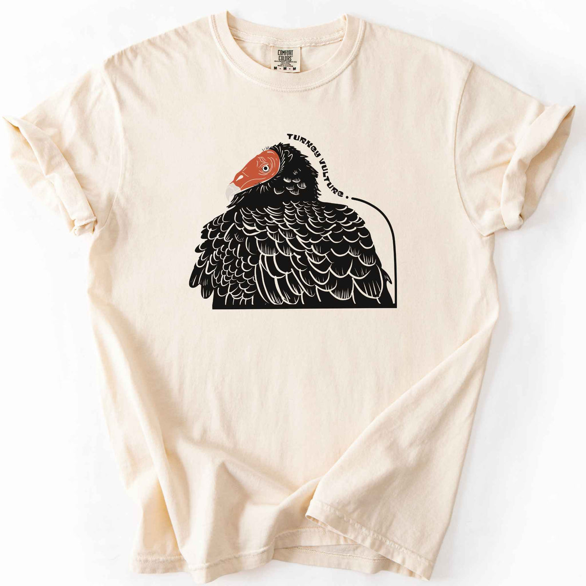 Ivory "Turkey Vulture" t-shirt on Comfort Colors tee, featuring a bold illustrated portrait of a turkey vulture with a curved text label. Birdwatcher and scavenger lover gift shirt for wildlife and nature enthusiasts.