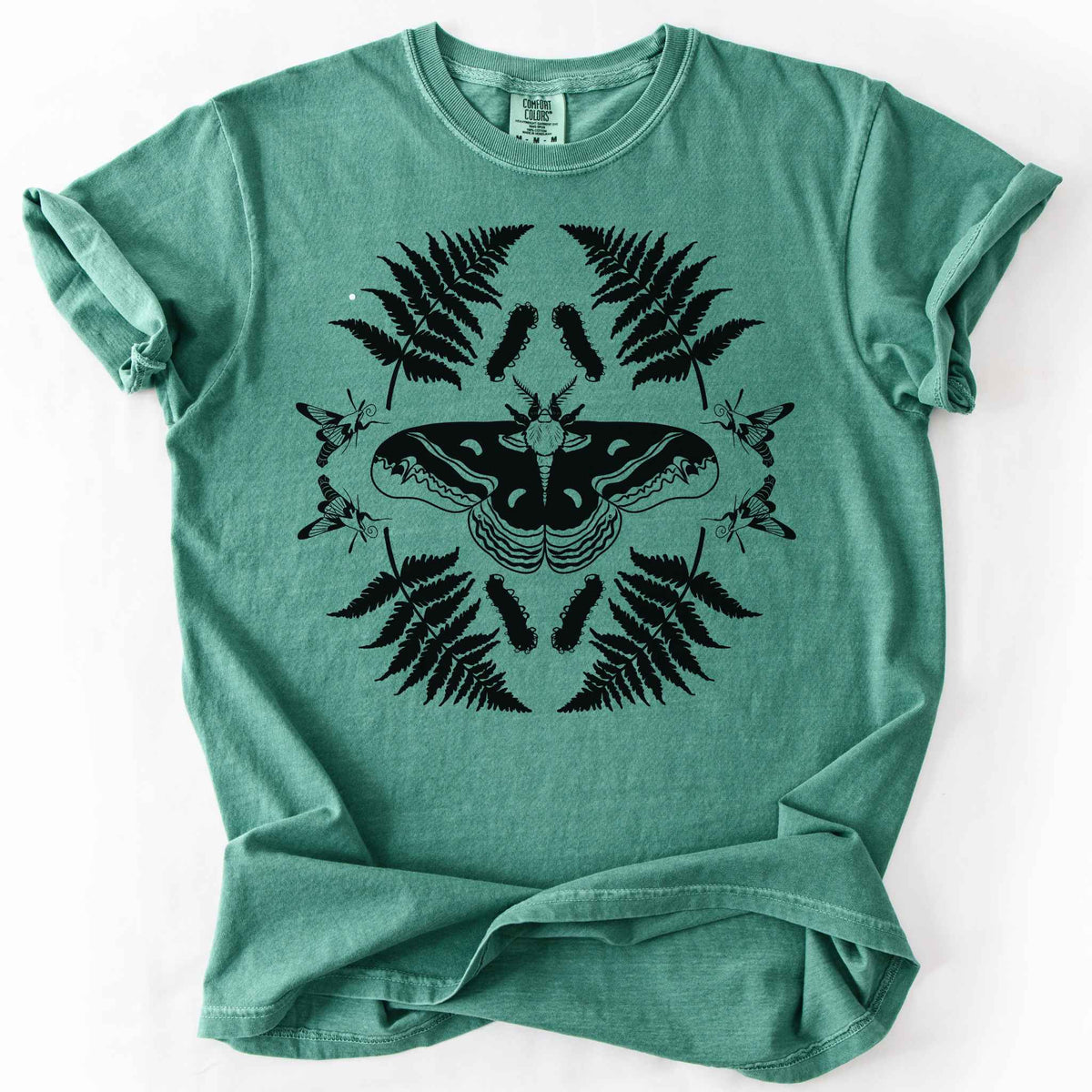 Light green "Cecropia moth" t-shirt on Comfort Colors tee, featuring a bold black symmetrical design of a moth surrounded by ferns and hummingbird moths in a mirrored botanical pattern. Nature lover and moth enthusiast gift shirt for entomology and cottagecore fans.
