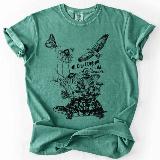 Light green "Fauna and Flora" t-shirt on Comfort Colors tee, featuring the words "all day I dream of wild wonder", and a nature scene in black line art style with a box turtle, mushrooms, wildflowers, a hawk, a butterfly, and a snail. Nature lover and forager gift shirt for cottagecore and wildlife enthusiasts.