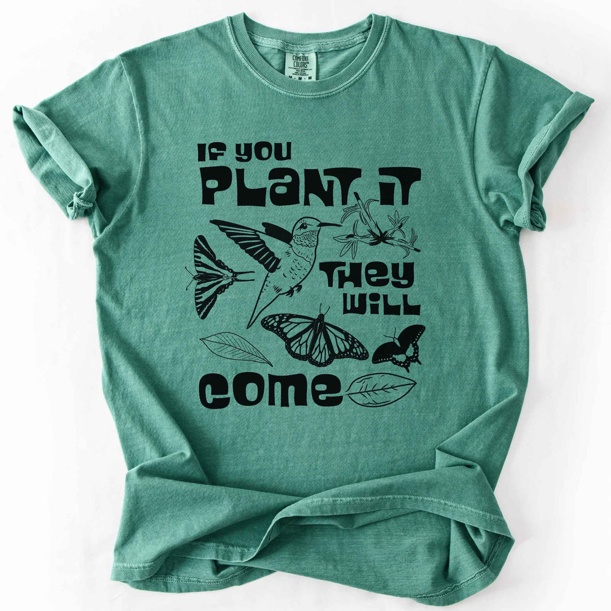 Light green "If You Plant It, They Will Come" t-shirt on Comfort Colors tee, featuring a hummingbird surrounded by butterflies and flowers with bold black lettering and line art style. Gardener and native plant gift shirt for pollinator conservation fans.