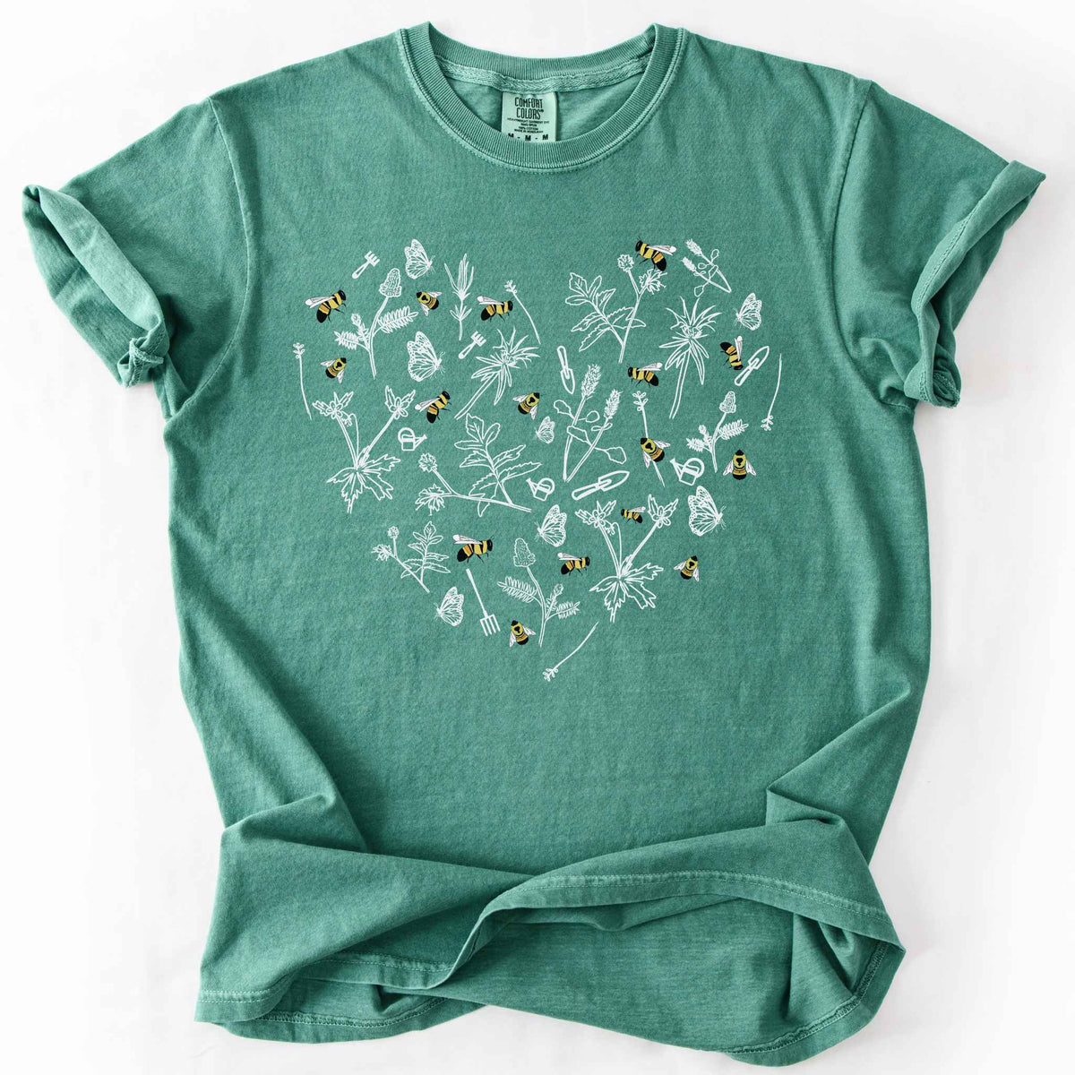 Light green "Rusty Patch Bumblebee" t-shirt on Comfort Colors tee, featuring a heart shaped arrangement of hand-drawn white wildflowers, garden tools, butterflies, and colorful bees. Gardener and pollinator lover gift shirt for bee conservation and nature enthusiasts.