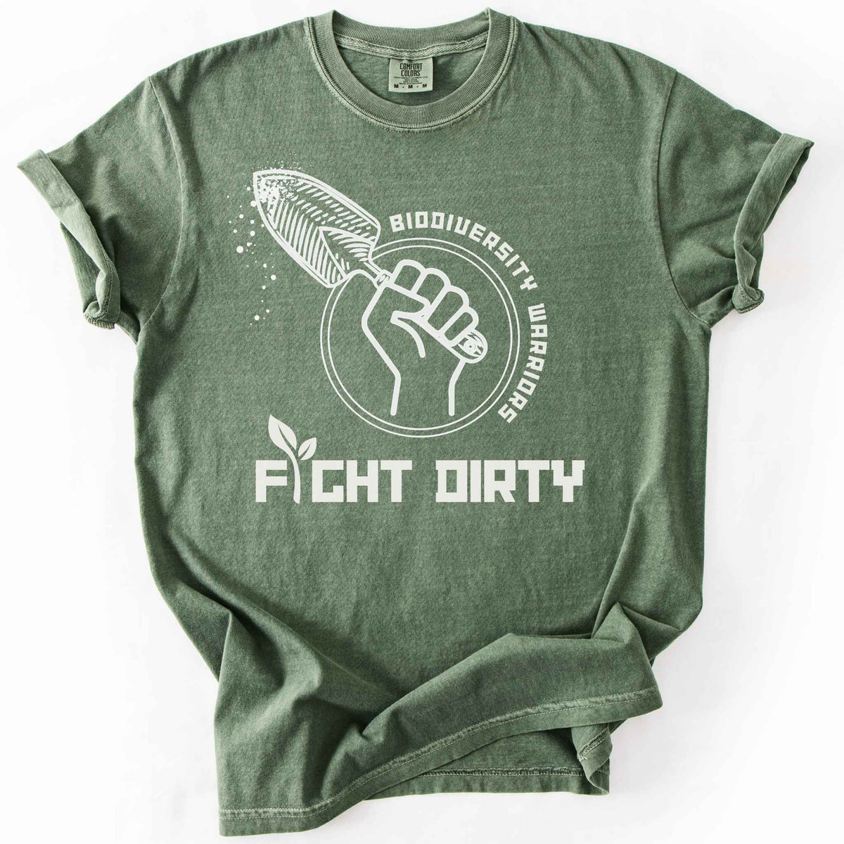 Moss "Biodiversity Warriors, Fight Dirty" t-shirt on Comfort Colors tee, featuring a raised fist gripping a garden trowel in a circular badge design. Gardener and conservation lover gift shirt for native plant and biodiversity enthusiasts.