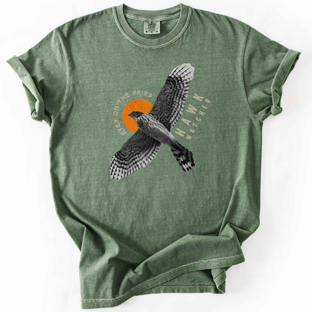 Moss "Hawk Watcher, Eyes on the Skies" t-shirt on Comfort Colors tee, featuring a flying hawk graphic with spread wings against an orange sun design- birdwatching and raptor lover gift shirt for bird enthusiasts.