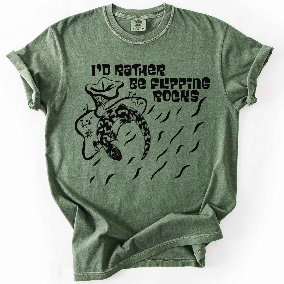 Moss "I'd Rather Be Flipping Rocks" t-shirt on Comfort Colors tee, featuring a bold graphic of a curled salamander with mushrooms in a groovy retro font. Funny herpetology gift shirt for salamander hunters and amphibian enthusiasts.