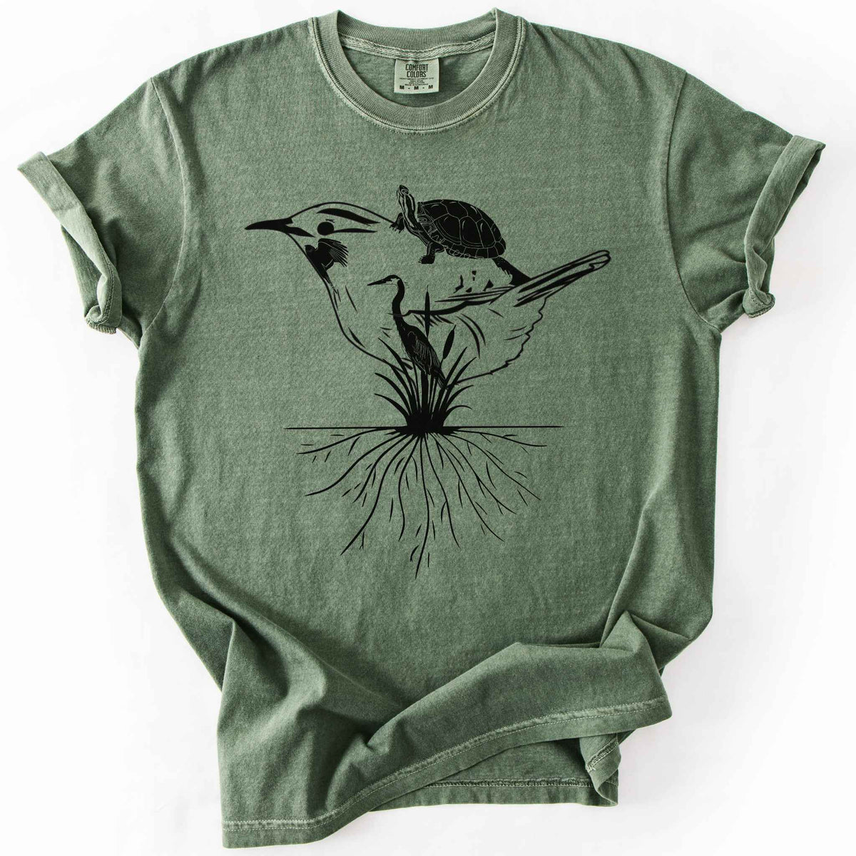 Moss "Marhlands Matter" t-shirt on Comfort Colors tee, featuring a surreal black line art style design blending a bird, turtle, heron, and cattail roots into one flowing wetland scene. Nature lover and wetland conservation gift shirt for birdwatching and wildlife enthusiasts.