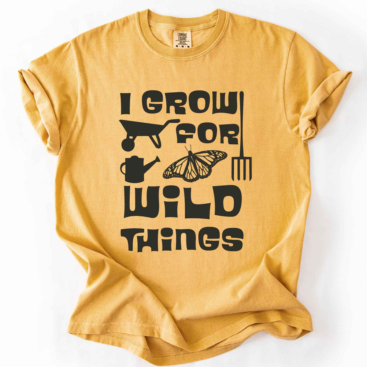 Mustard "I Grow for Wild Things" t-shirt on Comfort Colors tee, featuring a monarch butterfly with garden tool icons and bold black lettering text. Gardener and native plant gift shirt for pollinator conservation fans.