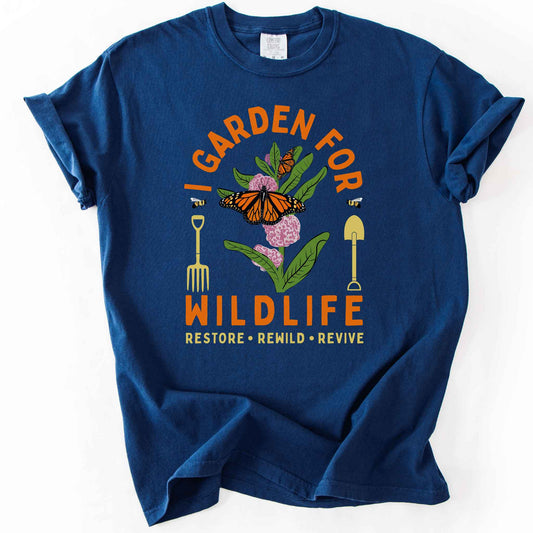 Navy "I Garden for Wildlife, Restore, Rewild, Revive" t-shirt on Comfort Colors tee, featuring monarch butterflies and bees on milkweed flowers flanked by garden tools in orange and gold tones. Gardener and native plant gift shirt for pollinator conservation fans.