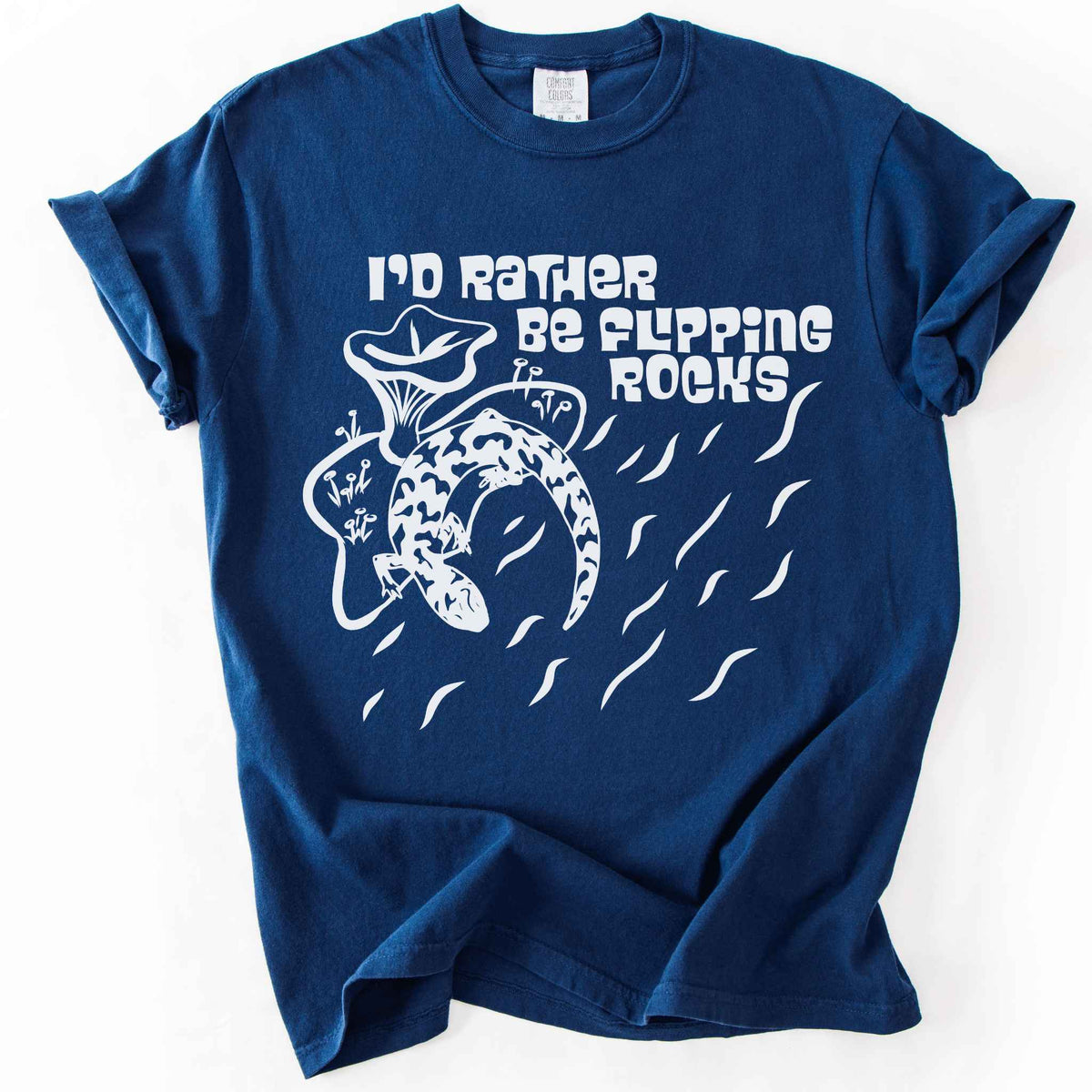 Navy "I'd Rather Be Flipping Rocks" t-shirt on Comfort Colors tee, featuring a bold graphic of a curled salamander with mushrooms in a groovy retro font. Funny herpetology gift shirt for salamander hunters and amphibian enthusiasts.