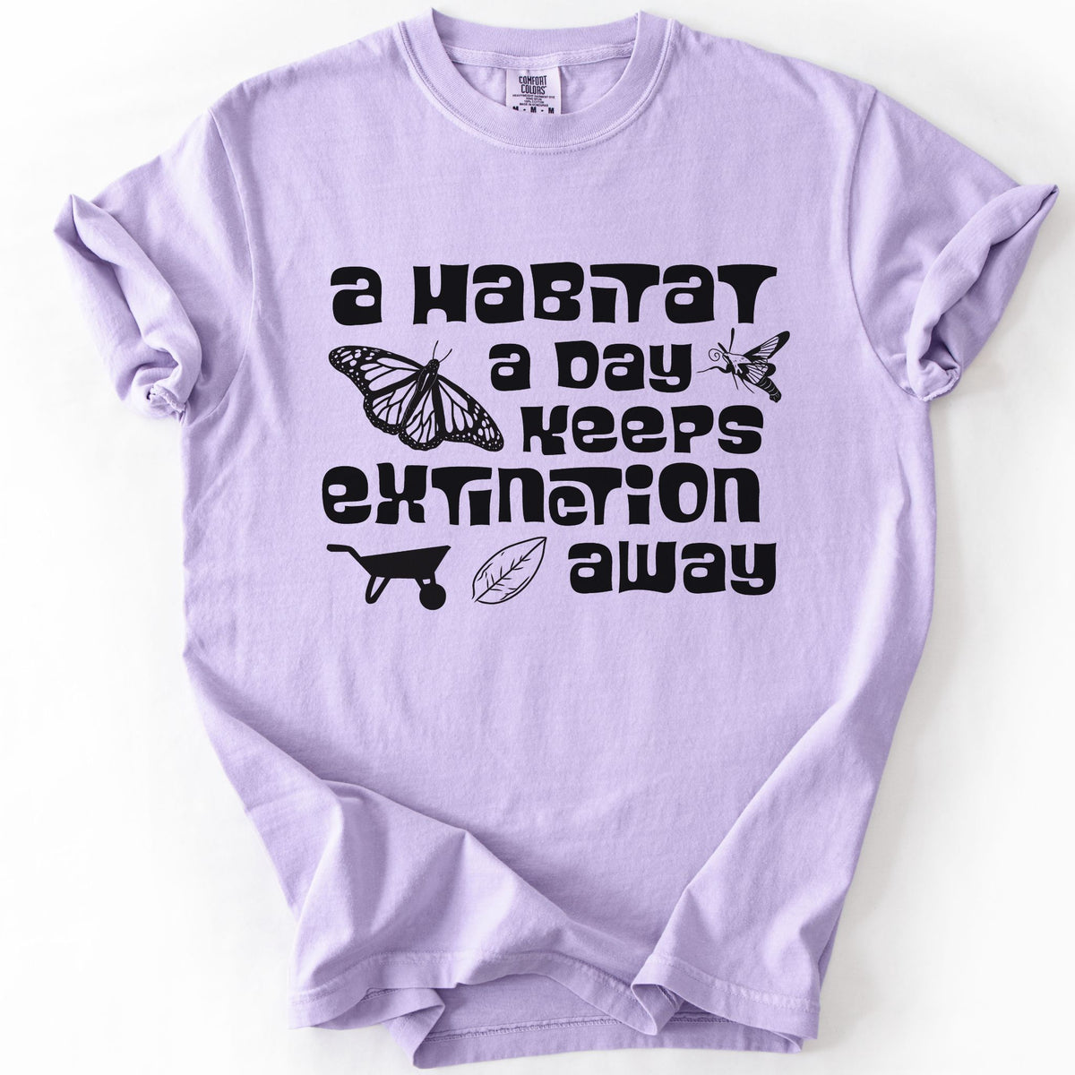 Orchid "A Habitat a Day Keeps Extinction Away" t-shirt on Comfort Colors tee, featuring a monarch butterfly, clearwing moth, wheelbarrow, and leaf icon with bold black lettering. Gardener and conservation gift shirt for native plant and pollinator enthusiasts.