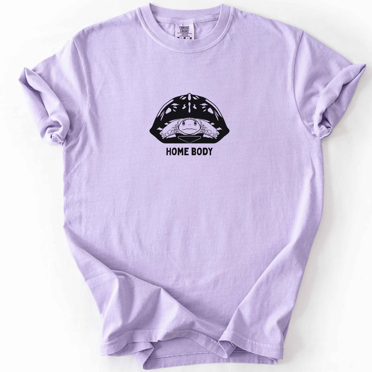 Orchid "Home Body" t-shirt on Comfort Colors tee, featuring a bold black graphic of a turtle peeking out from its shell above simple lettering. Funny turtle lover gift shirt for introverts and reptile enthusiasts.