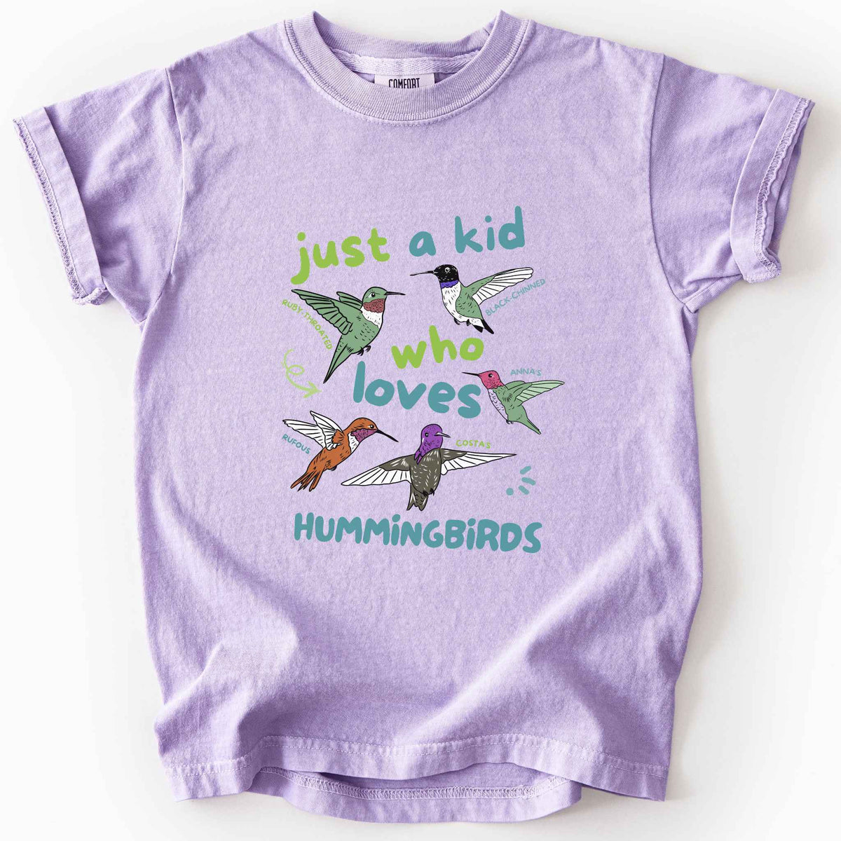 Orchid "Just a Kid Who Loves Hummingbirds" youth t-shirt on Comfort Colors tee, featuring five labeled hummingbird species including Ruby Throated, Anna's, and Costa's with playful green and blue lettering. Kids birdwatcher gift shirt for young nature lovers and budding wildlife enthusiasts.