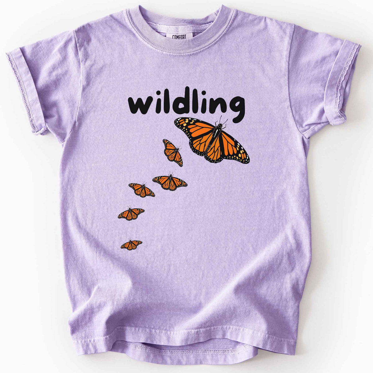 Orchid "Wildling" kids t-shirt on Comfort Colors Tee featuring six Monarch butterflies in an upward ascending pattern and bold black text. Nature inspired gift for kids and butterfly enthusiasts. 
